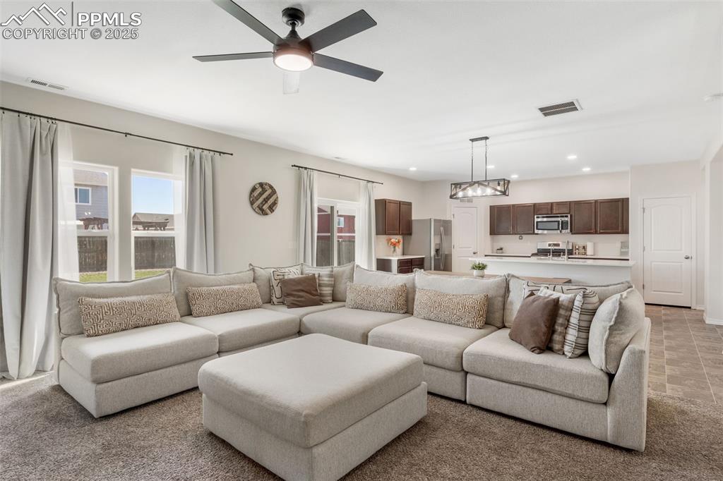 Living area with light carpet, ceiling fan, and recessed lighting