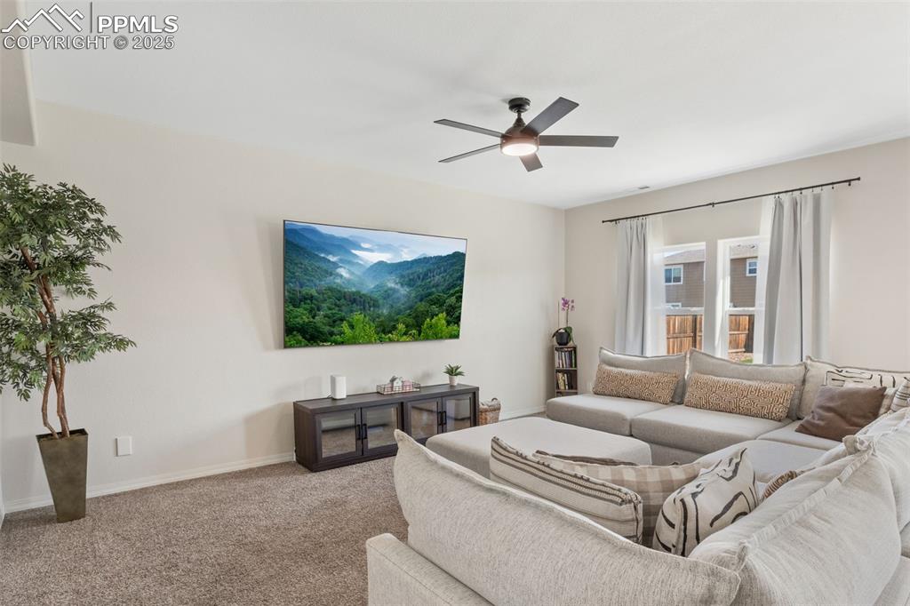 Living room with carpet and a ceiling fan