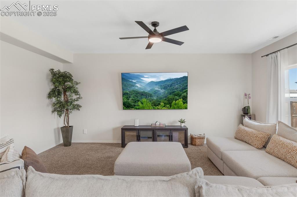 Carpeted living room featuring baseboards and a ceiling fan