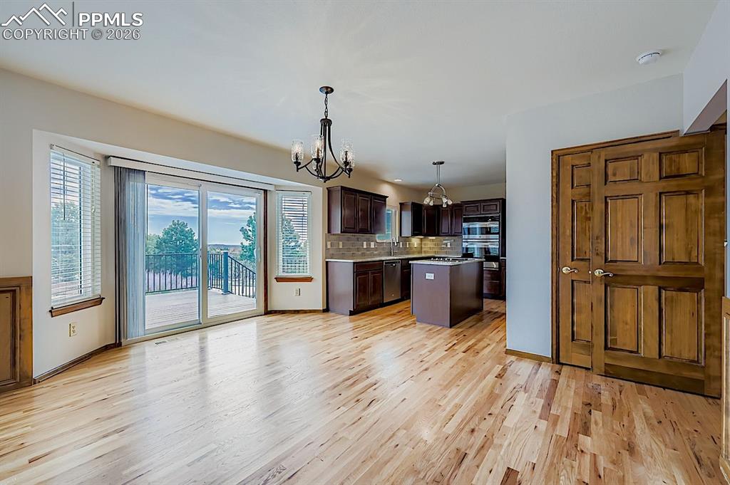 Kitchen with dark brown cabinetry, tasteful backsplash, pendant lighting, a chandelier, and a kitchen island