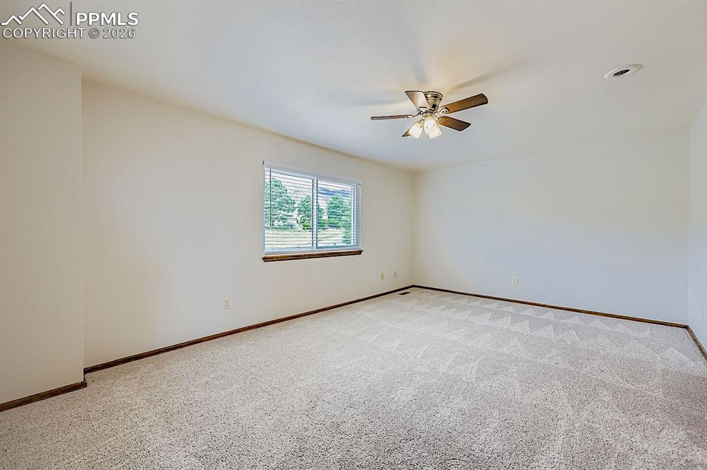 Carpeted empty room featuring baseboards and a ceiling fan