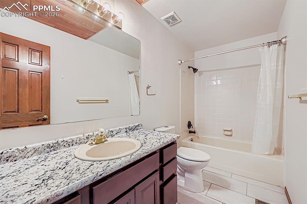 Full bath featuring shower / bath combination with curtain, vanity, and light tile patterned floors
