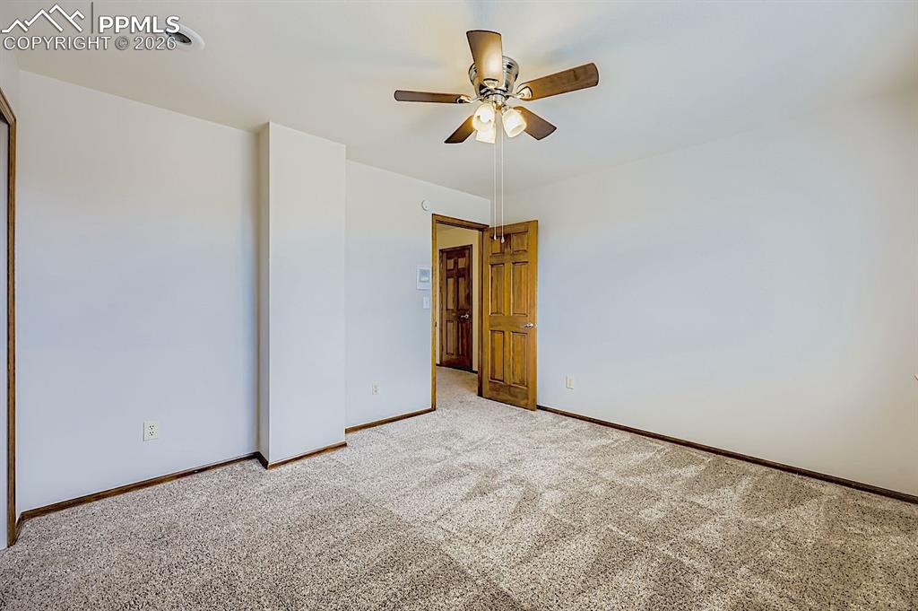 Carpeted spare room with baseboards and a ceiling fan