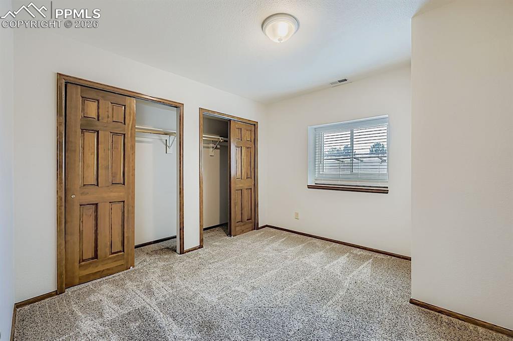 Unfurnished bedroom featuring multiple closets and light colored carpet
