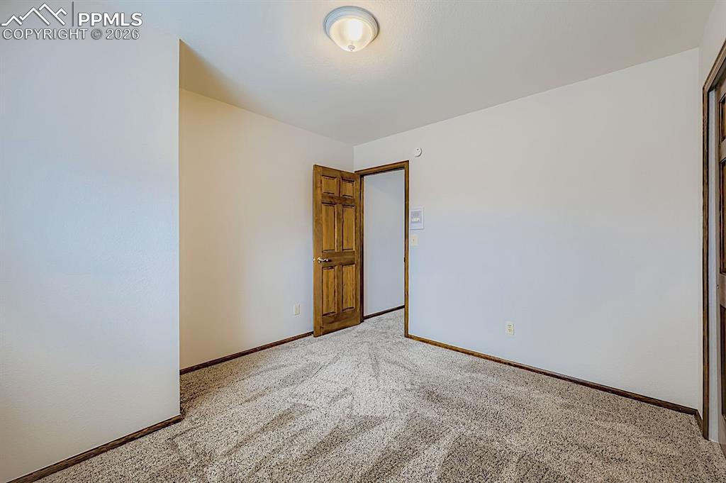 Spare room featuring carpet flooring and baseboards