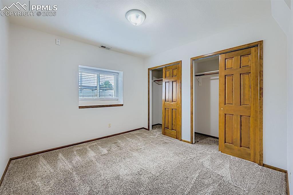 Unfurnished bedroom featuring multiple closets and carpet floors