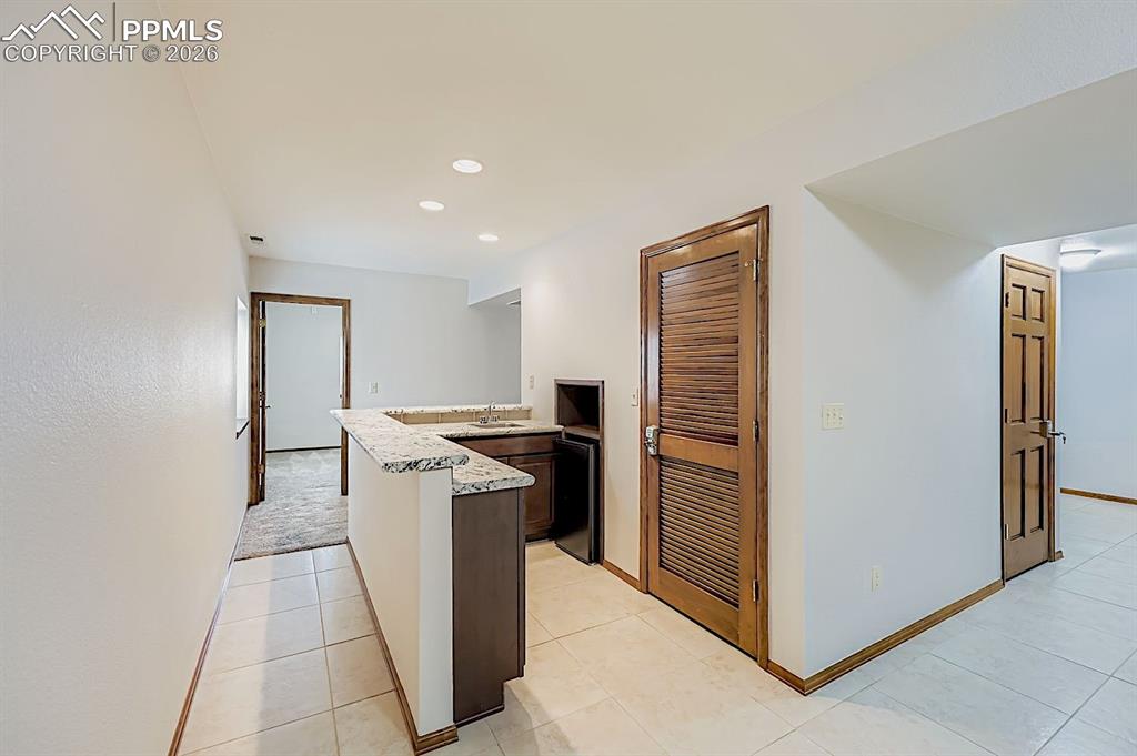 Kitchen with a peninsula, recessed lighting, light stone countertops, and light tile patterned floors