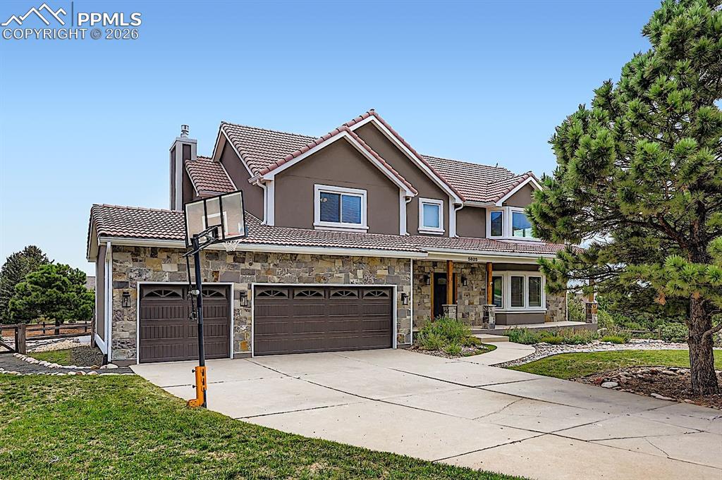 View of front of house featuring a chimney, driveway, a tiled roof, stucco siding, and a porch