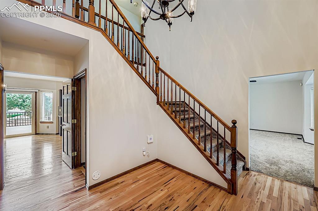 Staircase featuring a chandelier, wood finished floors, and a towering ceiling