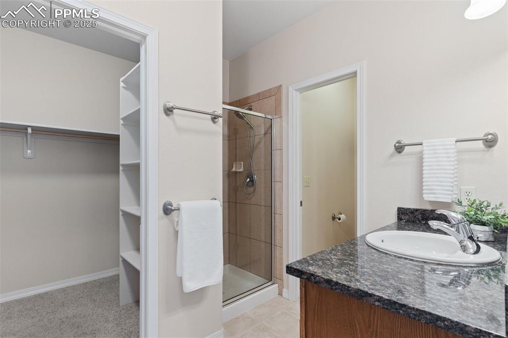 Full bathroom featuring a spacious closet, a stall shower, and vanity