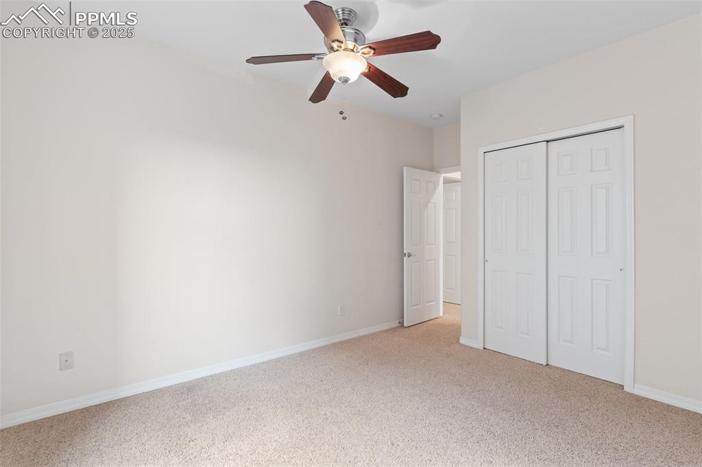 Unfurnished bedroom featuring a closet, light colored carpet, and a ceiling fan