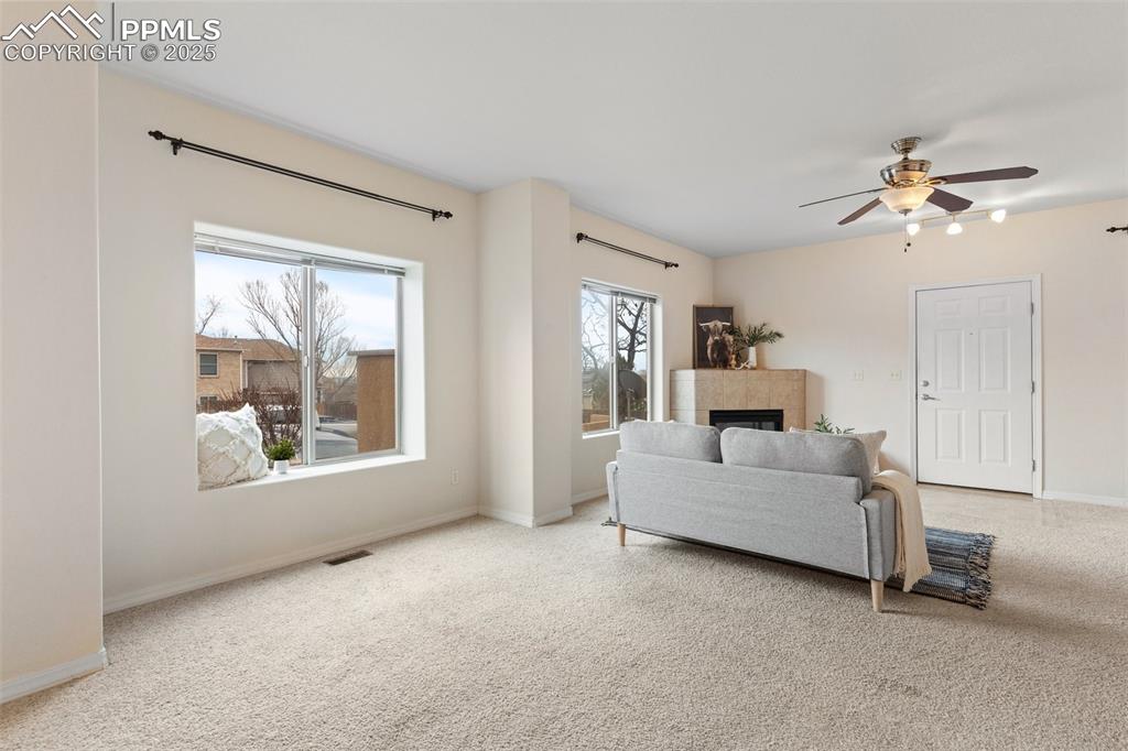 Living area with carpet floors, a fireplace, and ceiling fan