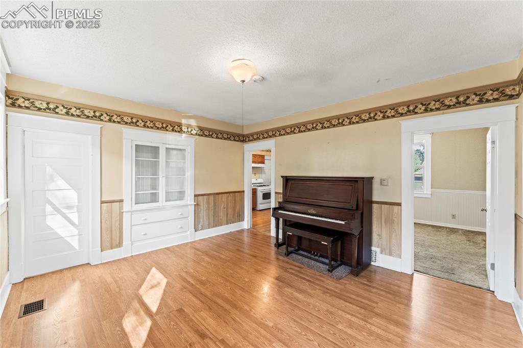 Sitting room featuring a textured ceiling, wainscoting, light wood finished floors, and wooden walls