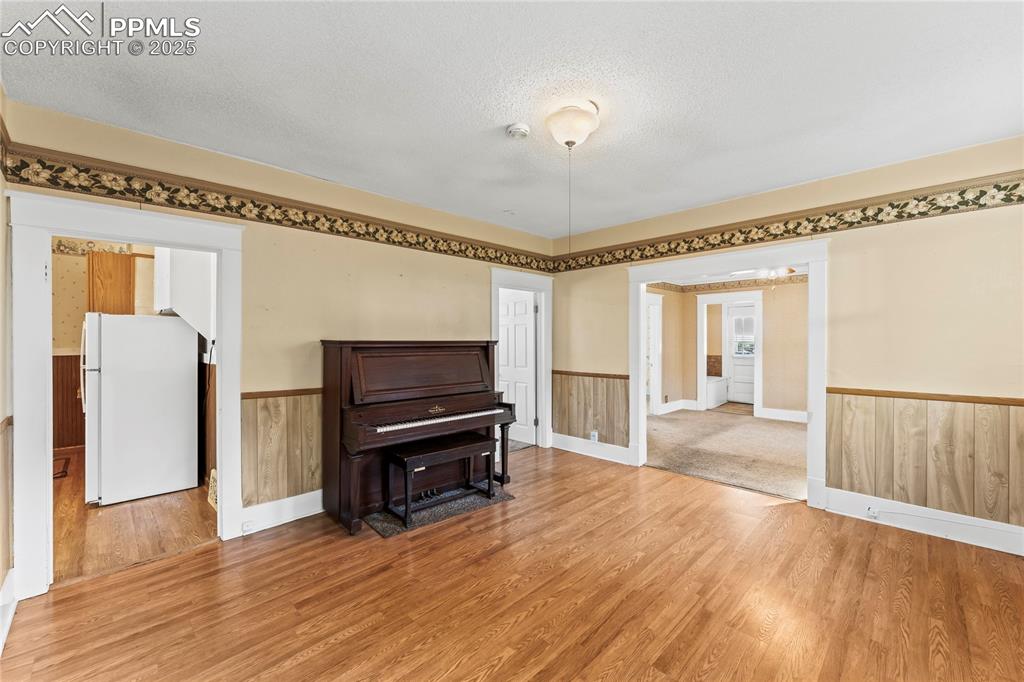 Living area with wainscoting, a textured ceiling, and wood finished floors