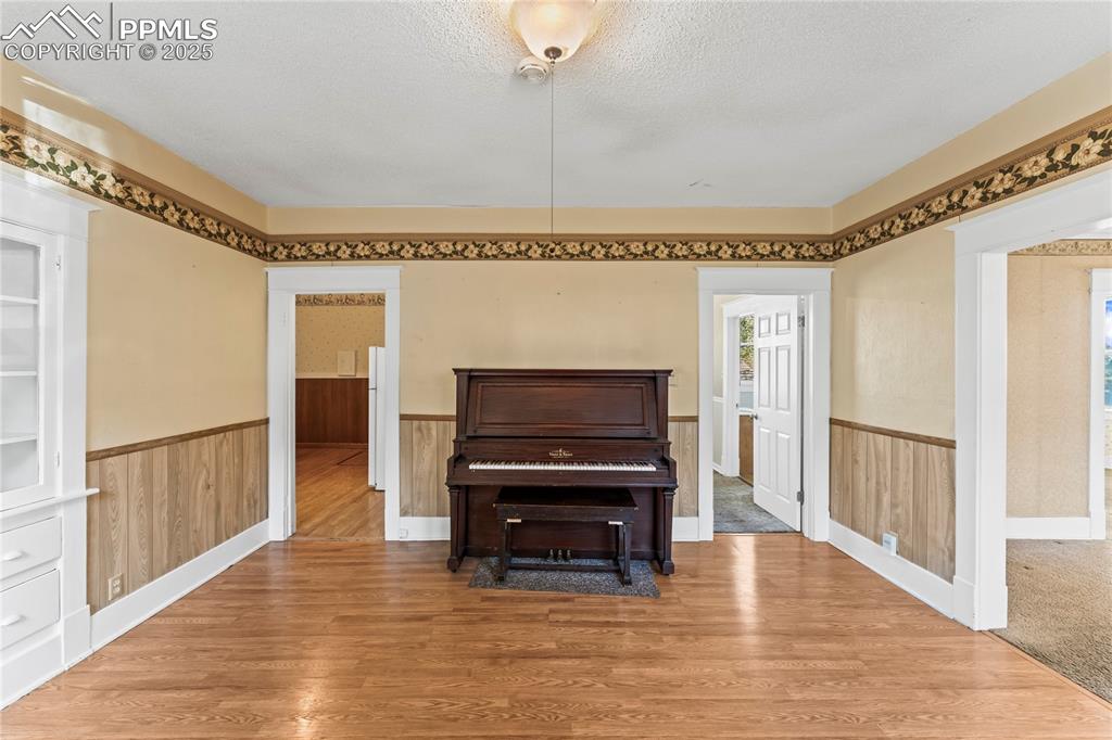 Living area featuring wood finished floors, a wainscoted wall, and a textured ceiling