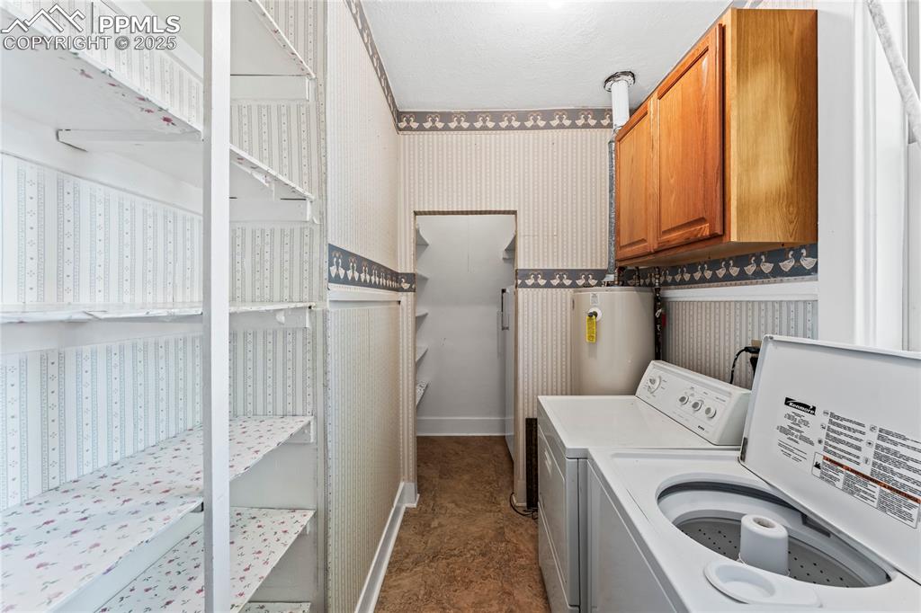 Washroom with wallpapered walls, gas water heater, independent washer and dryer, and cabinet space