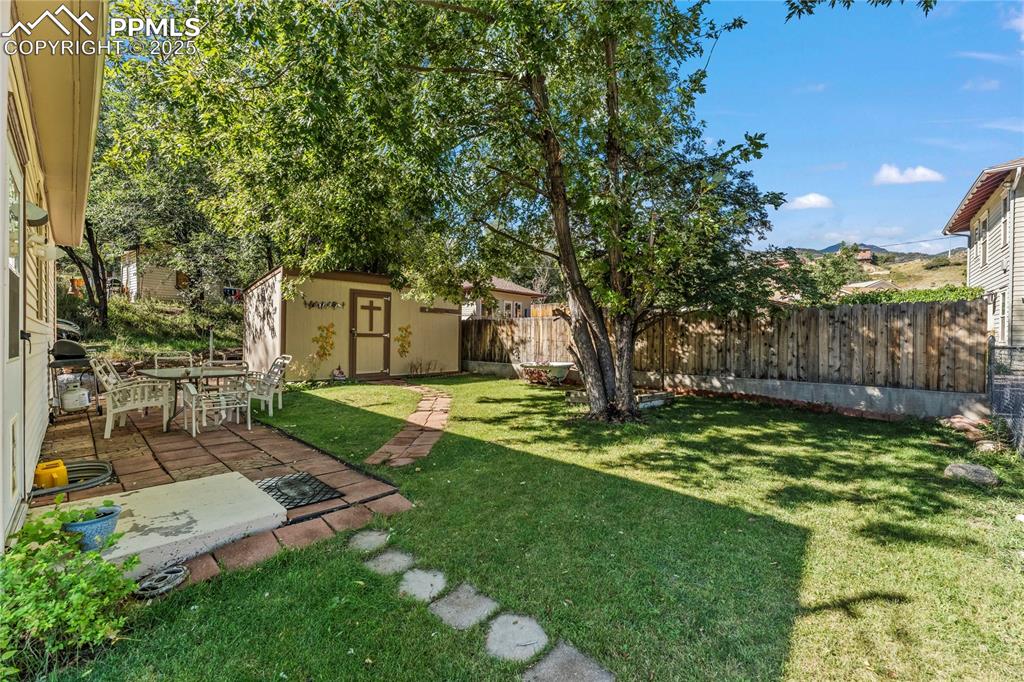 Fenced backyard featuring a storage shed and a patio area