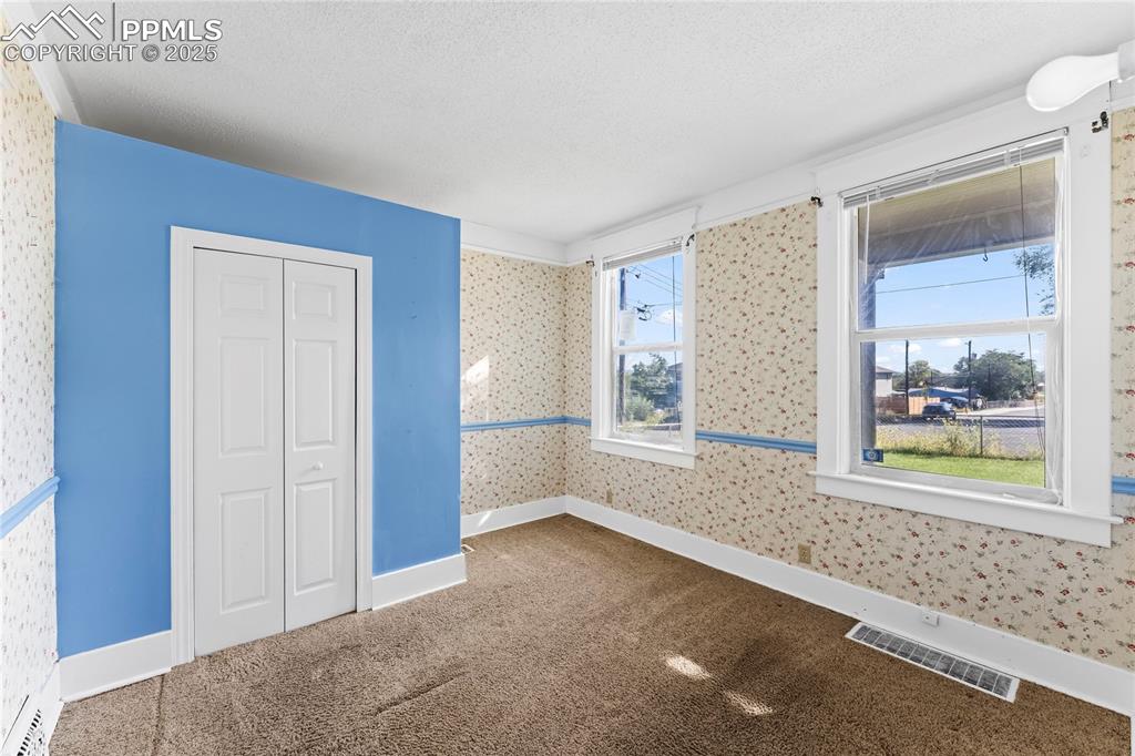 Unfurnished bedroom with carpet flooring, wallpapered walls, and a textured ceiling