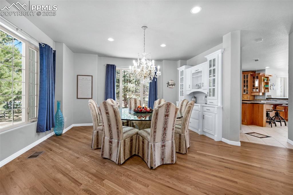 Dining area featuring visible vents, light wood-style flooring, plenty of natural light, and an inviting chandelier