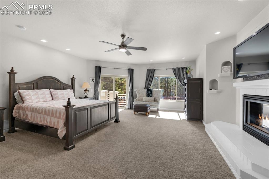 Bedroom with a ceiling fan, baseboards, recessed lighting, a tiled fireplace, and carpet flooring