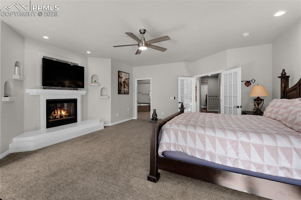 Bedroom with a glass covered fireplace, recessed lighting, french doors, carpet floors, and baseboards