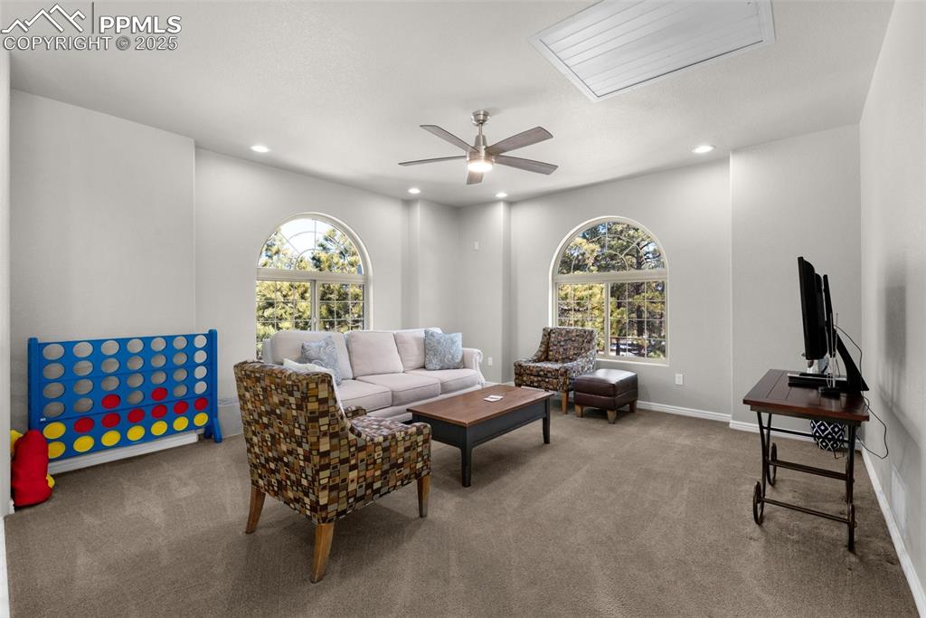Carpeted living area featuring a ceiling fan, recessed lighting, baseboards, and a wealth of natural light