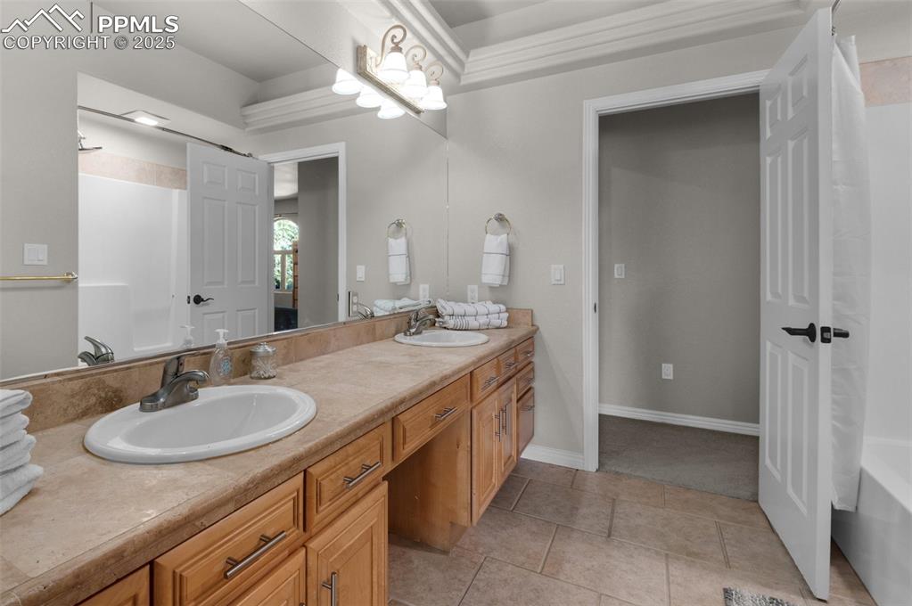 Bathroom featuring double vanity, tile patterned floors, baseboards, and a sink
