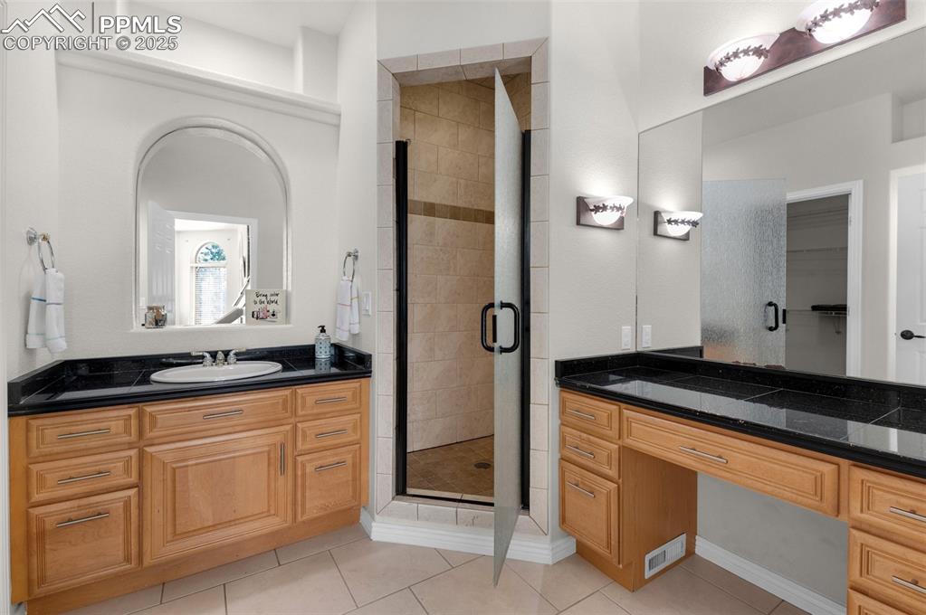 Bathroom featuring tile patterned floors, a shower stall, and vanity