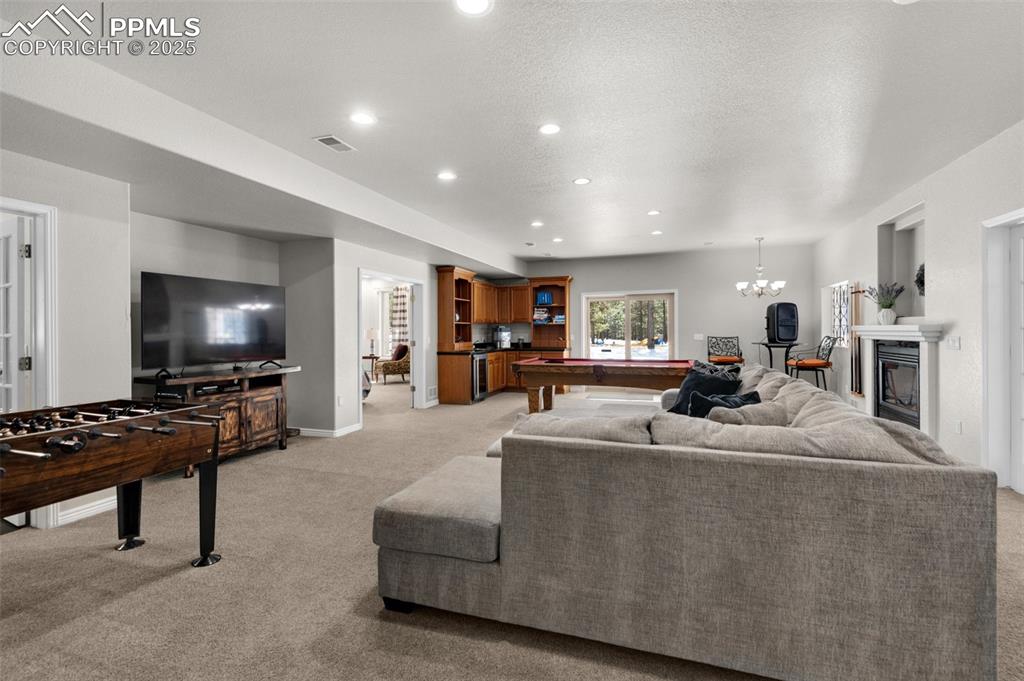 Living area with light carpet, recessed lighting, a glass covered fireplace, a textured ceiling, and billiards