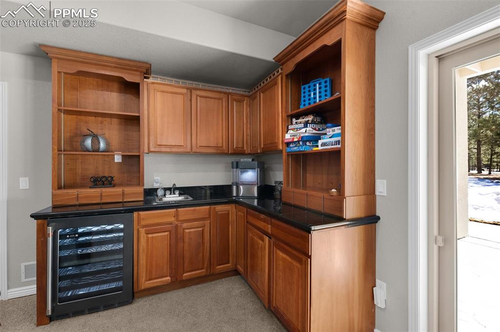 Bar with a sink, wine cooler, and light carpet