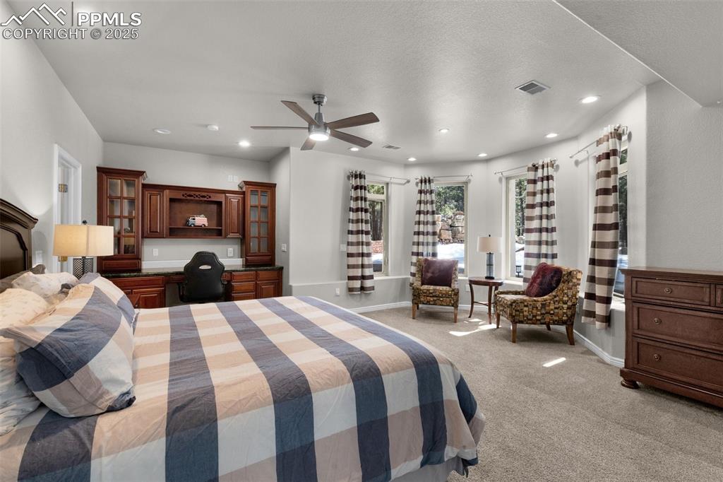 Bedroom with a ceiling fan, baseboards, built in study area, recessed lighting, and light carpet
