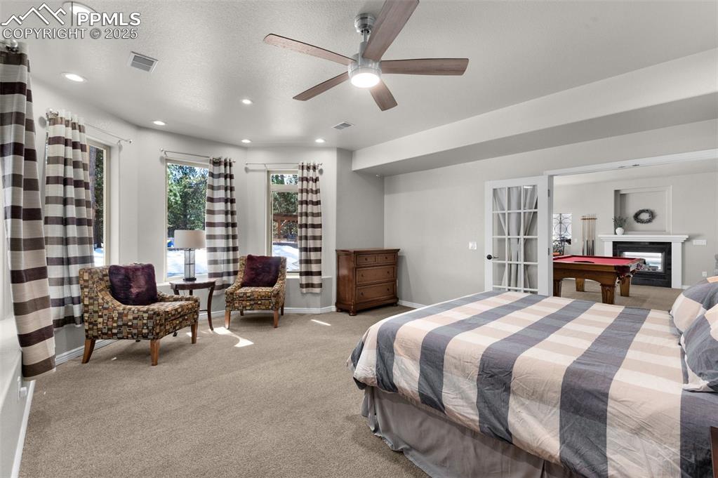 Bedroom with visible vents, a glass covered fireplace, recessed lighting, baseboards, and light colored carpet