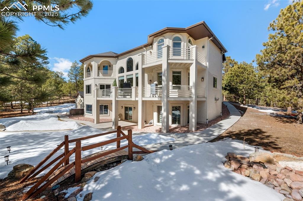 Snow covered house with a balcony and stucco siding