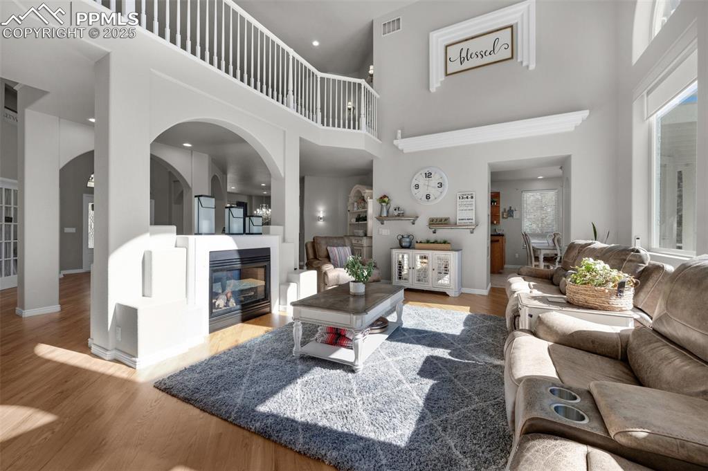 Living room with a glass covered fireplace, a high ceiling, baseboards, and wood finished floors