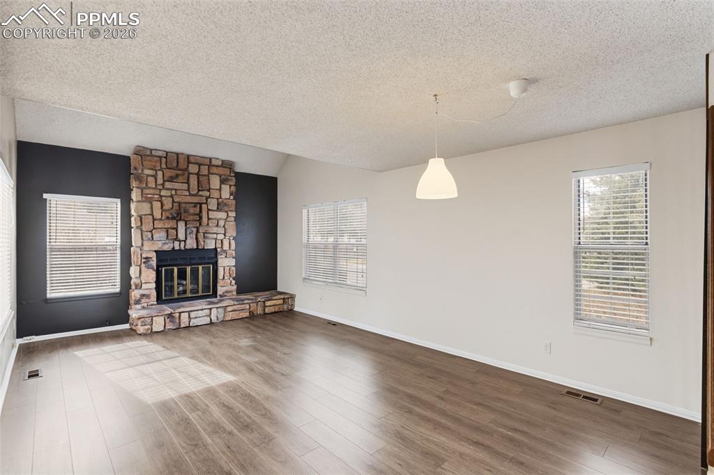 Living room featuring wood-style floors and a stone fireplace