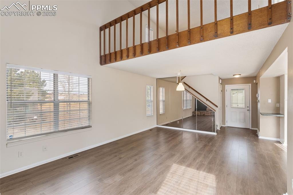 Living room with a high ceiling, wood-style floors, and plenty of natural light