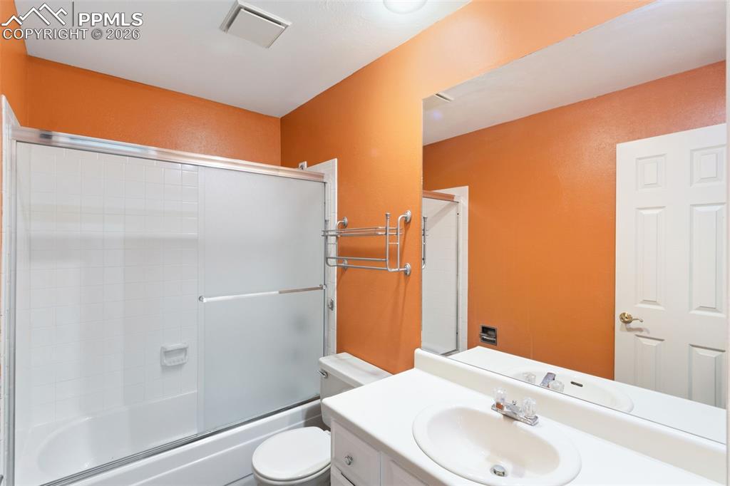 Main-level bathroom with vanity and bath / shower combo with glass door