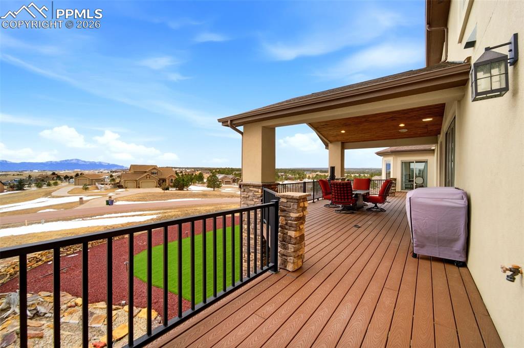 Deck featuring a residential view, outdoor dining area, a mountain view, and a lawn