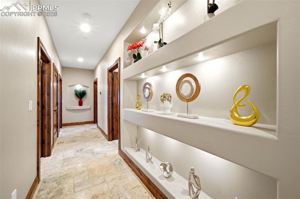 Hallway featuring stone tile floors and baseboards