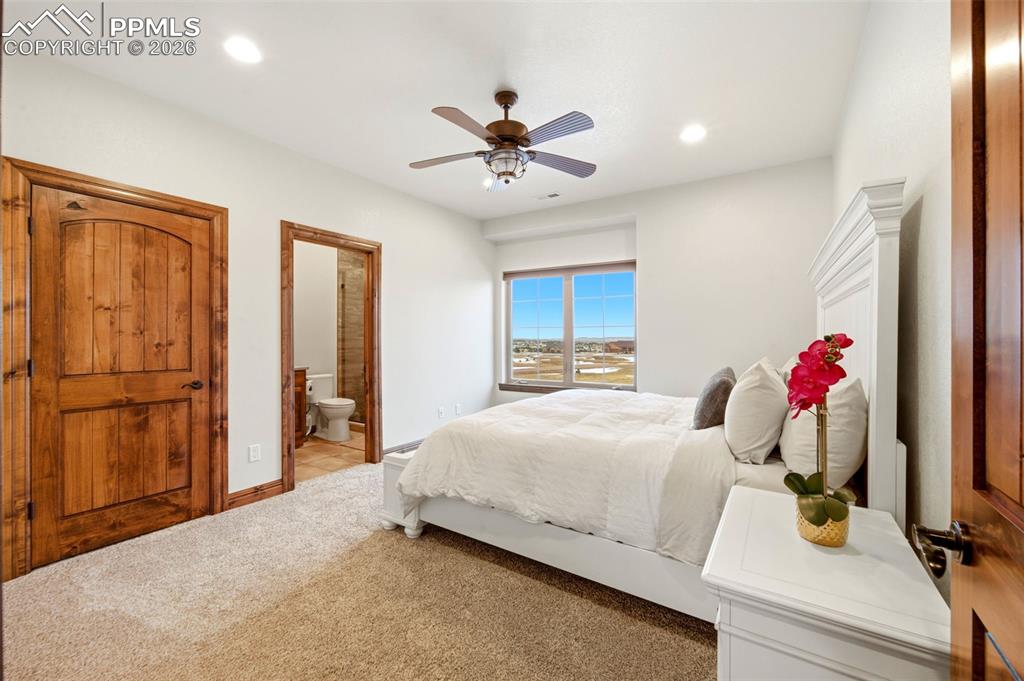 Bedroom with a ceiling fan, ensuite bathroom, light carpet, and recessed lighting