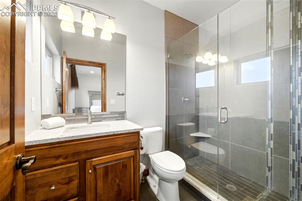 Full bath with vanity, a shower stall, ensuite bath, and healthy amount of natural light