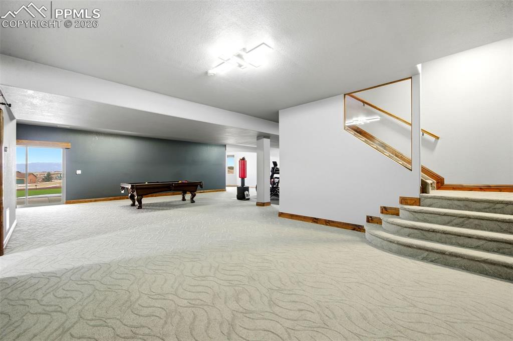 Recreation room featuring light colored carpet, billiards table, and a textured ceiling