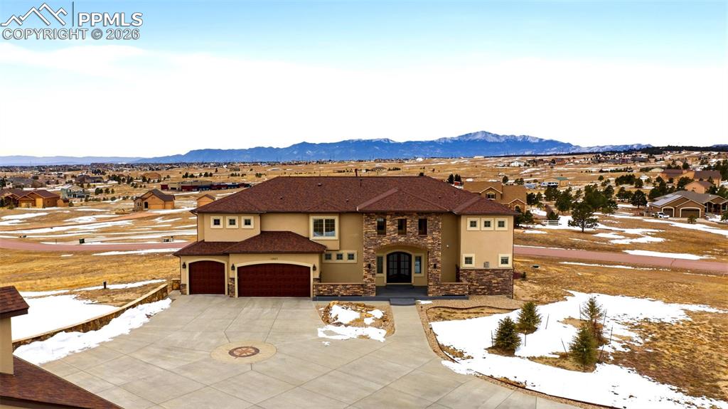 Mediterranean / spanish home featuring stone siding, an attached garage, a residential view, and concrete driveway