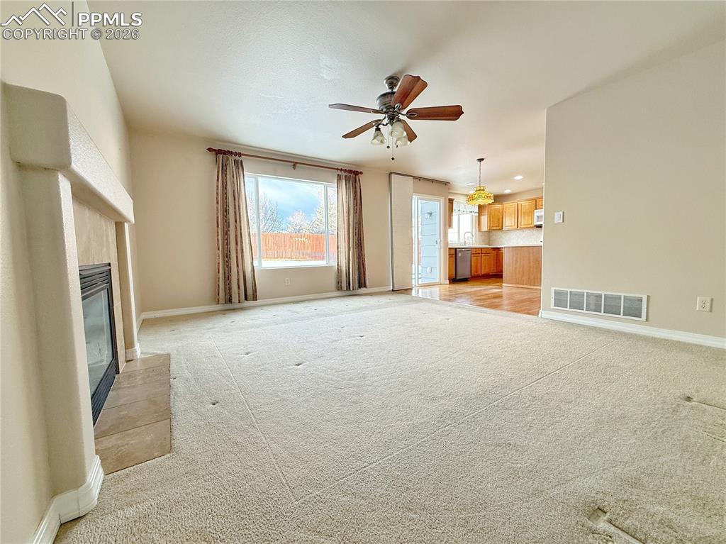 Unfurnished living room with a fireplace, ceiling fan, light colored carpet, and recessed lighting