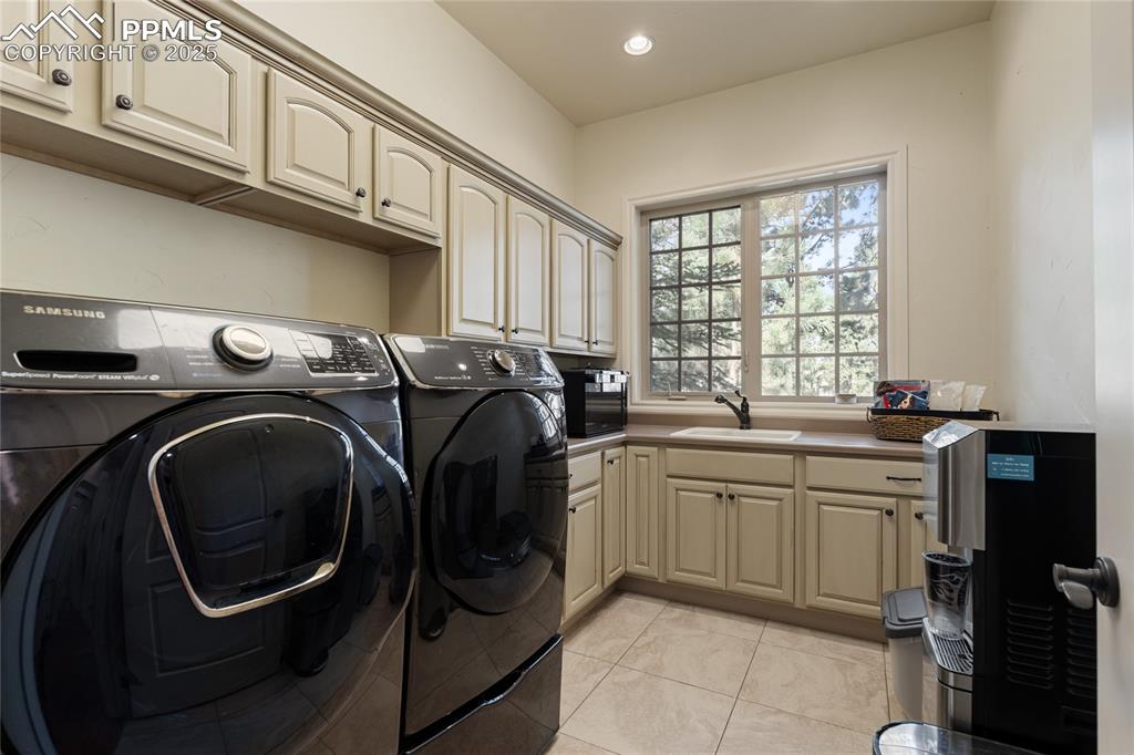 Main level laundry room with sink and plenty of cabinetry.