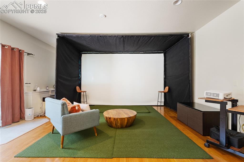 Cinema with golf simulator, wood finished floors, and recessed lighting