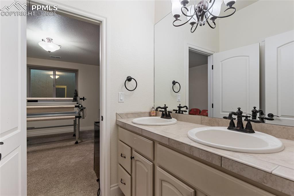 Full bath with double vanity and a chandelier
