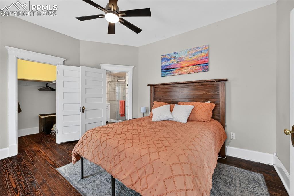 Large primary bedroom with wood flooring, ceiling fan, large walk-in closet and en-suite bathroom