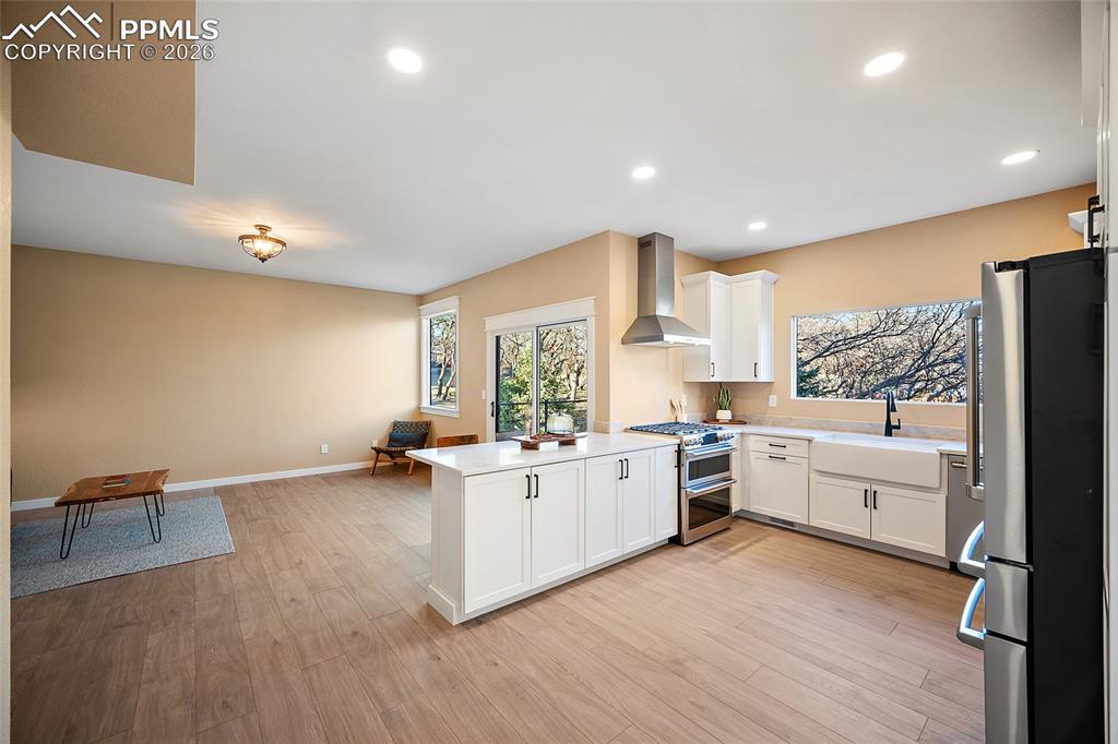 Kitchen with a peninsula island, stainless steel Cafe appliances, newly installed white cabinetry, open floor plan, and LVP flooring