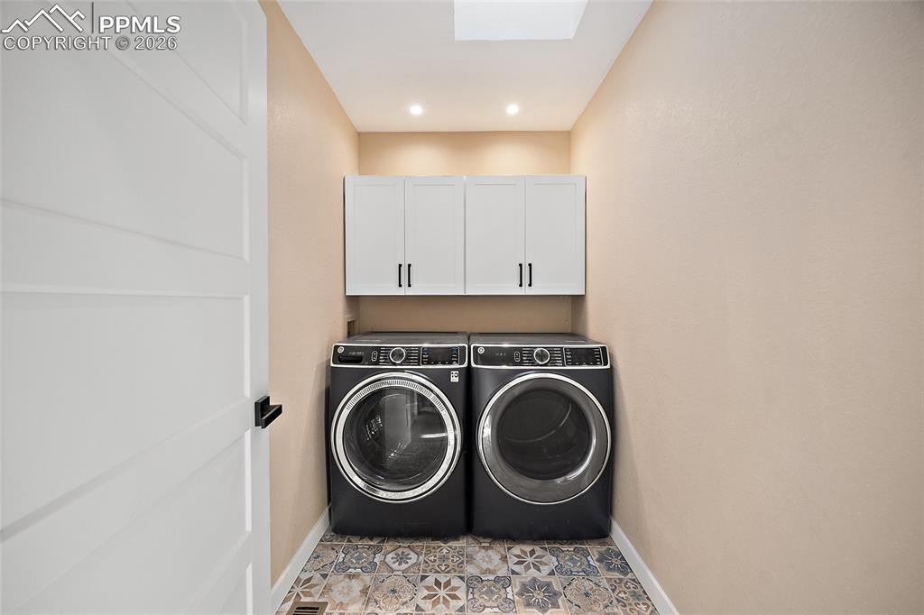 Laundry area featuring washer and dryer, cabinet space, skylight, recessed lighting, and light tile patterned flooring